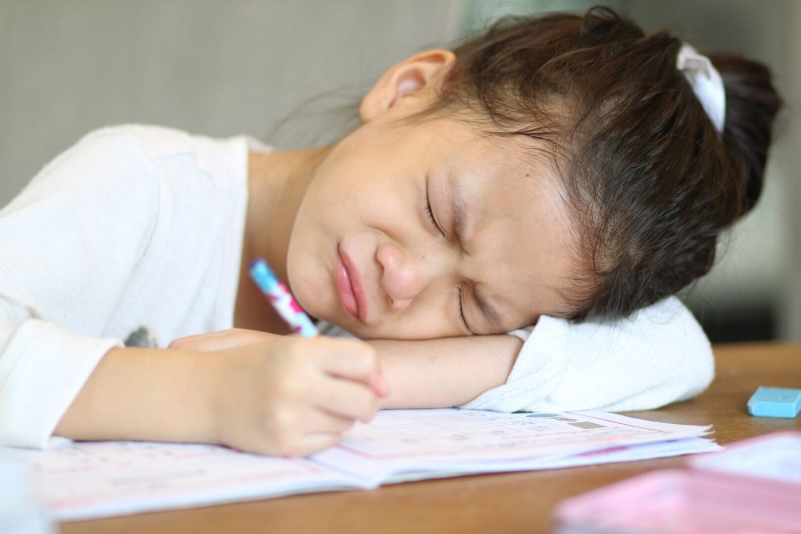 Sad student writing in a notebook with her head on the table